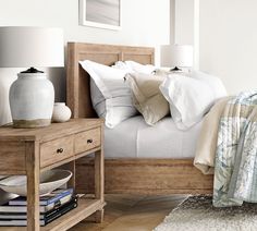 a bed with white linens and pillows on top of it next to a night stand