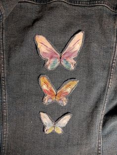 three butterflies are on the back of a jean jacket