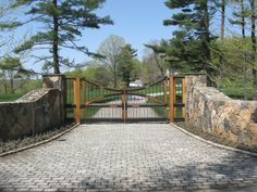 a stone driveway with a wooden gate and brick walkway