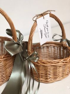 two wicker baskets with ribbons and tags on them sitting next to each other in front of a white wall