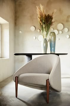 a chair sitting in front of a table with vases on it