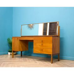 a wooden desk with a mirror on top and a potted plant next to it