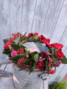 a bucket filled with flowers on top of a wooden table