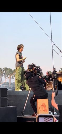 a man standing on top of a stage next to another person holding a microphone and recording