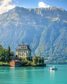 a house on an island in the middle of a lake with mountains in the background