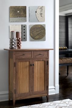 a wooden cabinet sitting on top of a hard wood floor next to a white wall