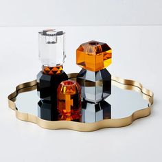 an unusual shaped glass and gold tray with two crystal cubes on it's side