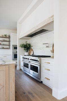 a kitchen with white cabinets and stainless steel stove top oven, built in shelving