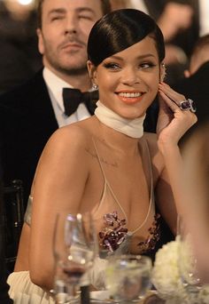 a woman in a halter top sitting at a table next to a man wearing a tuxedo