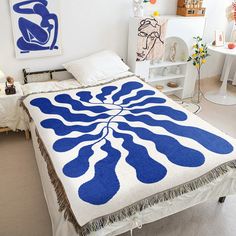 a blue and white bedspread on a bed in a room with two paintings