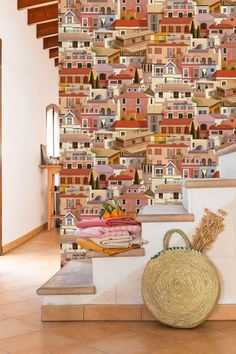 a wall with many houses on it and a basket in front of the stair case