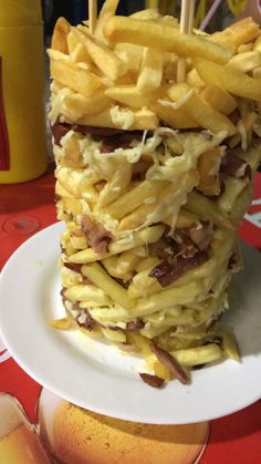 a stack of french fries sitting on top of a white plate next to an apple