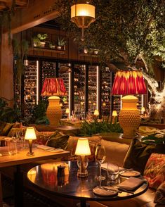 a restaurant with tables, chairs and lamps in the middle of it at night time