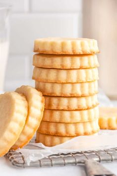 a stack of shortbread cookies next to a glass of milk on a white table