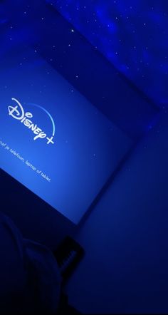 the logo for disney plus is projected on a screen in a dark room with blue lighting