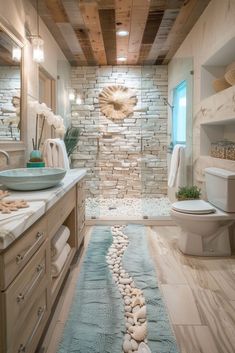 a bathroom with stone walls and flooring, along with a blue rug on the floor