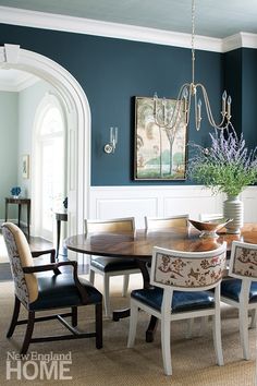 an elegant dining room with blue walls and white trimmings, is pictured in this image