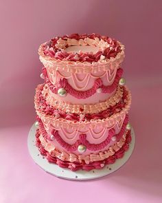 a three tiered cake with pink frosting and pearls on it's sides