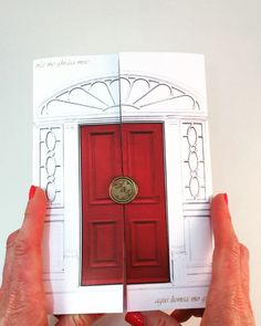 two hands holding up an open book with a red door on the front and side