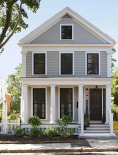 a white two story house with black shutters on the front door and porches