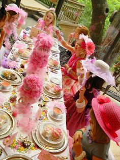 a group of women sitting around a table covered in plates and cups filled with food