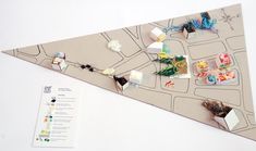 a paper triangle with pins and magnets attached to it on a white surface next to a map