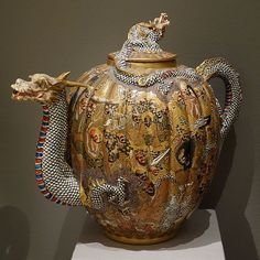 a large vase with a snake on the top and other designs on it's side