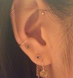 a close up of a person's ear with three different piercings on it