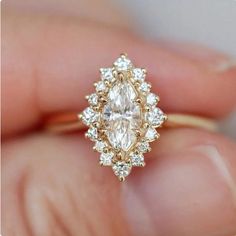 a woman's hand holding an engagement ring with a pear shaped diamond in the center