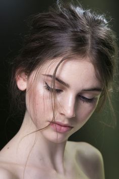 a young woman with her eyes closed and hair blowing in the wind, looking down