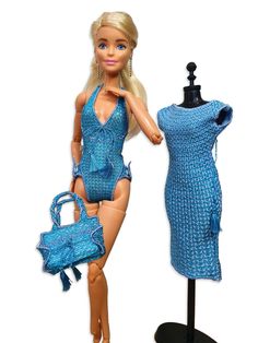 a barbie doll is posed next to a dress and purse