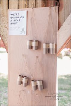 there are four cups hanging on the side of a wooden structure with string attached to it