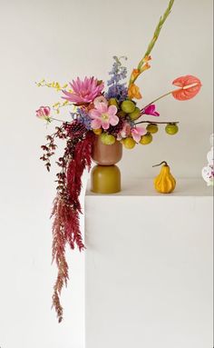 a vase filled with lots of colorful flowers on top of a white table next to a small figurine