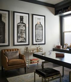 a living room filled with furniture and framed pictures on the wall above a desk in front of a window