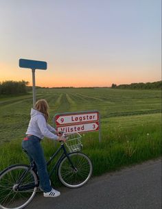 a woman riding a bike next to a road sign