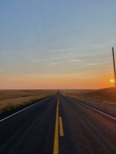 the sun is setting on an empty road in the middle of nowhere, with no traffic