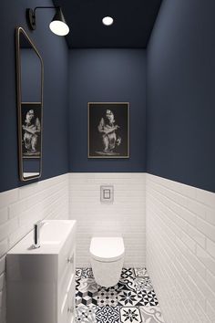 a white toilet sitting next to a sink in a bathroom under two pictures on the wall