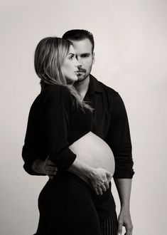 a man and woman standing next to each other holding their stomachs in front of the camera