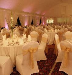 the banquet hall is decorated with white linens and gold sashes