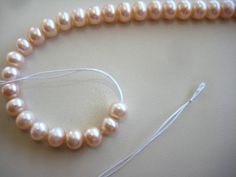 a single strand of white pearls with a string attached to it, on a table