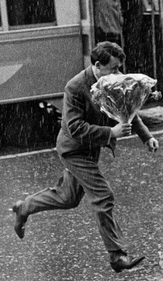 a man running in the rain with an umbrella over his head and a bag on his back