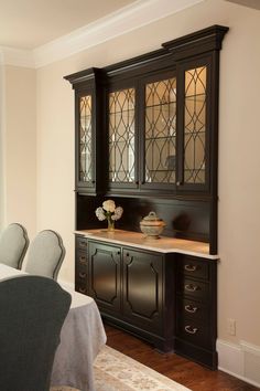 a dining room table and chairs in front of a china cabinet with stained glass doors