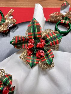 a white napkin with red and green bows on it next to other napkins in the shape of bells