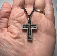 a person holding a cross in their hand with two rings on it's sides