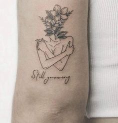 a woman's arm with a tattoo on it that reads, still growing and flowers