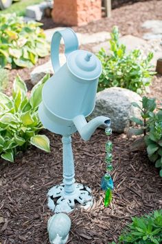 a blue watering can sitting in the middle of a garden