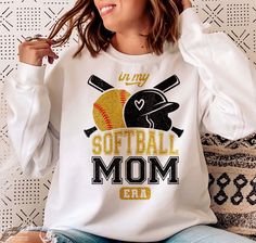 a woman sitting on a couch wearing a softball mom shirt