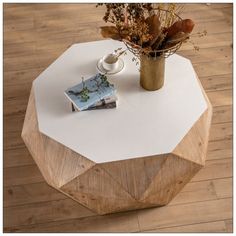 a wooden table with a magazine on it next to a vase filled with dried flowers