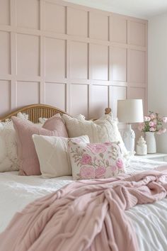 a bed with pink and white pillows on top of it in front of a wooden headboard