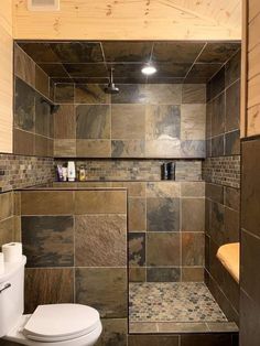 a bathroom with a toilet, shower and tiled walls on the wall is shown in this image